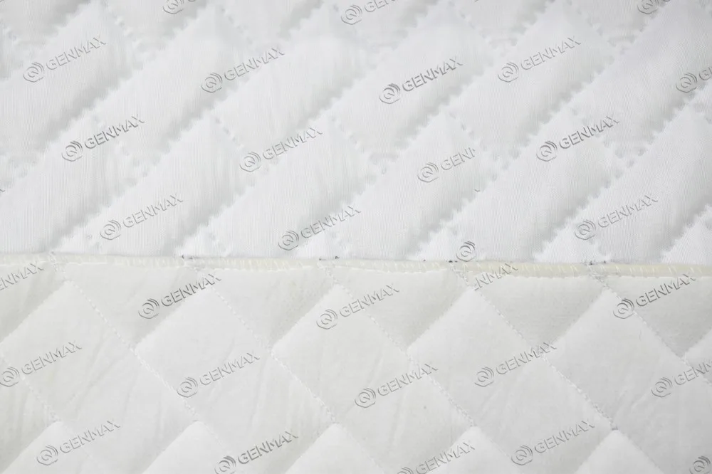 Close-up of multi-needle quilted mattress border fabric showing visible thread and fraying at seam edge