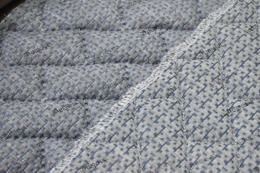 Wider view of multi-needle quilted mattress border showing fraying seam and inconsistent pattern alignment