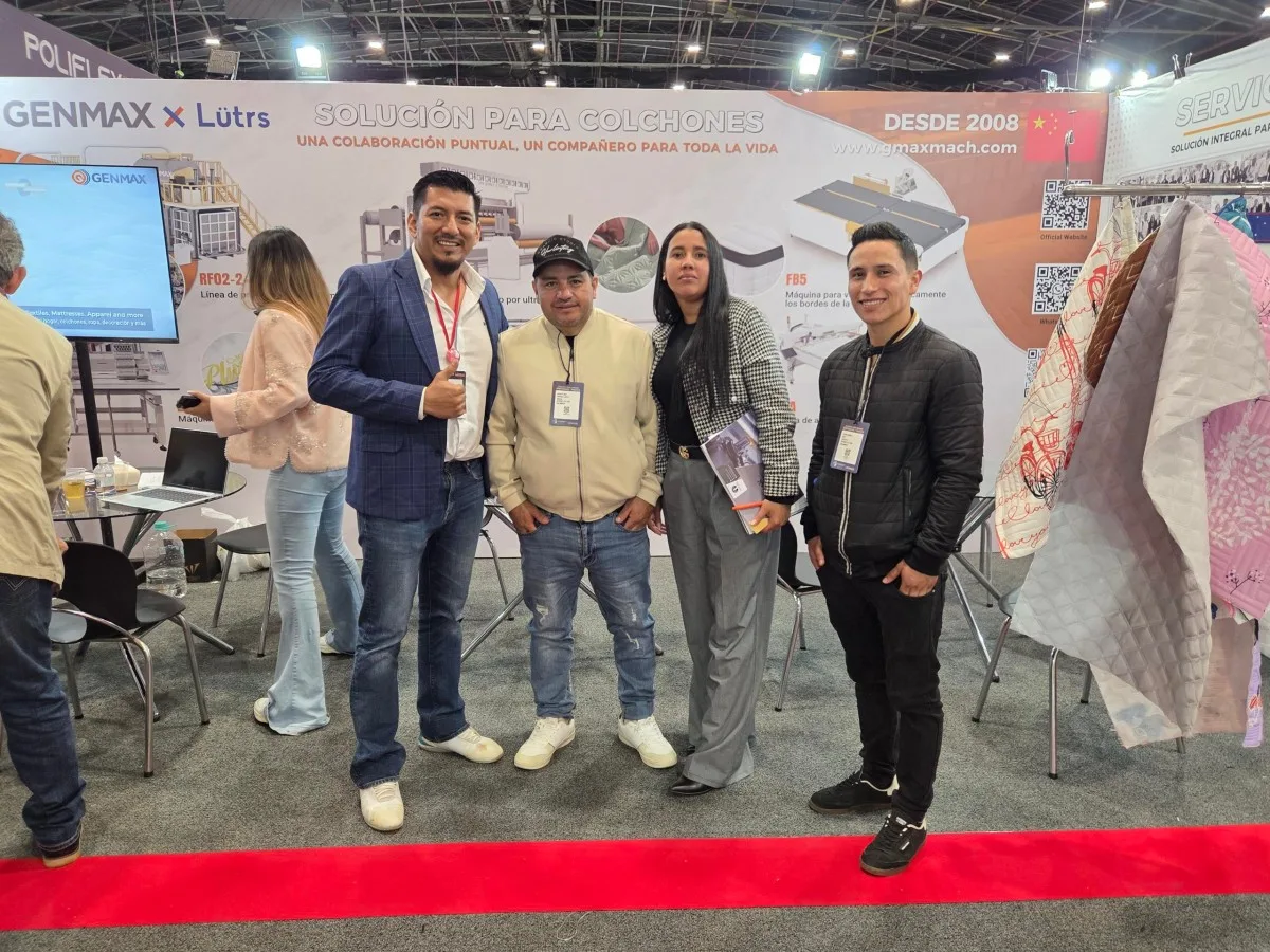 GENMAX representative and Latin American industry professionals holding product brochures and posing at the GENMAX x Lütrs booth at Interzum Bogotá 2026